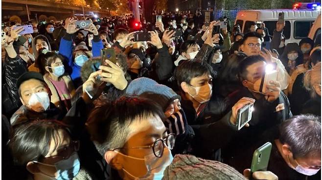 중국 당국의 코로나19 봉쇄 정책에 항의하는 시위가 전국 주요 도시로 번진 가운데 베이징에서는 철야 시위를 벌인 시민들이 28일 새벽에 해산을 거부하고 모여 있다. 베이징/AFP 연합뉴스