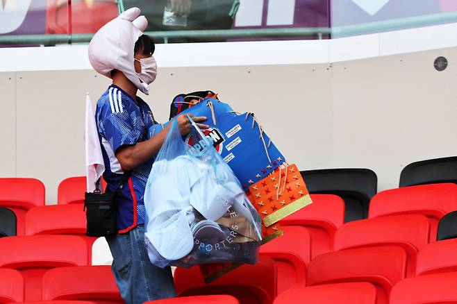 일본의 한 축구 팬이 27일(현지시간) 카타르 알라이얀 아흐마드 빈 알리 스타디움에서 2022 카타르 월드컵 조별리그 E조 일본과 코스타리카의 경기가 끝난 후 경기장을 청소하고 있다. [AFP]