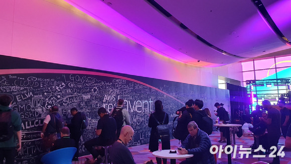 28일(현지시간) 미국 라스베이거스에서 개막한'AWS 리인벤트 2022(re:Invent 2022)'에 참가한 사람들이 AWS 리인벤트 로고가 그려진 벽면 앞에서 사진을 찍고 있다. [사진=박진영 기자]