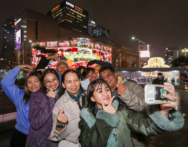 필리핀 단체 관광객들이 신세계본점 크리스마스 미디어 파사드 앞에서 기념촬영을 하고 있다. /사진제공=신세계면세점