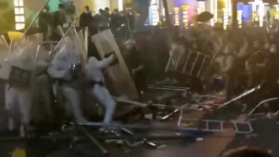 애플 협력업체 폭스콘의 중국 정저우 공장 직원들이 23일 경찰과 충돌하고 있다. [AP=연합뉴스]