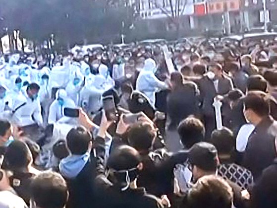지난 23일 애플 아이폰의 세계 최대 생산 기지인 중국 허난성 정저우시 폭스콘 공장에서 노동자들이 방호복을 입은 보안요원, 경찰들과 충돌하고 있다. AFP=연합뉴스