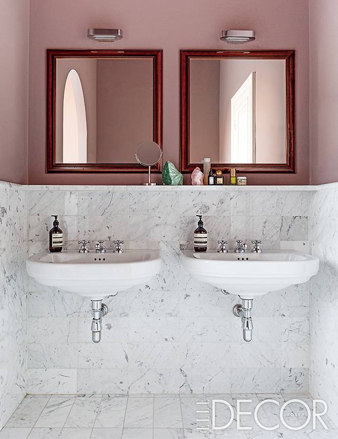 마블 패턴의 조각 타일과 더스티 핑크 컬러의 도장으로 꾸민 욕실. 두 개의 앤티크 거울을 달았다.