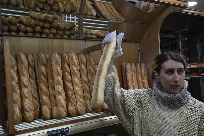 프랑스 베르사유의 빵가게 주인이 29일(현지시각) 바게트를 손님에게 들어 보이고 있다. AP 연합뉴스
