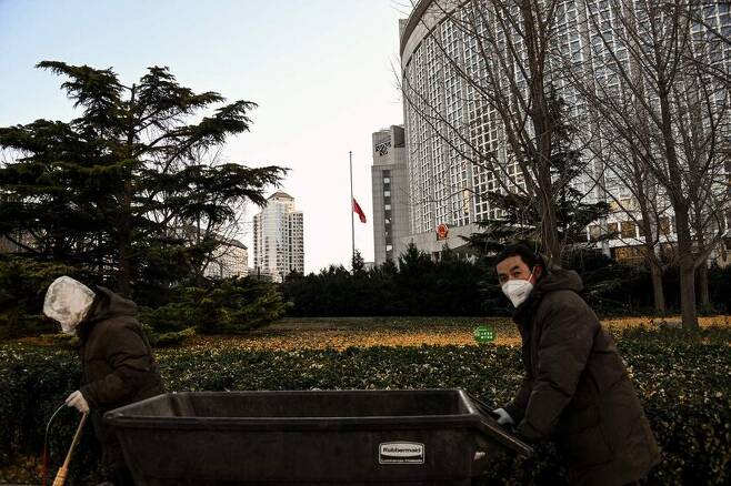 1일 장쩌민 전 중국 국가주석의 사망으로 조기가 게양된 중국 베이징 외교부 앞을 주민들이 수레를 끌고 가고 있다. 베이징/AFP 연합뉴스