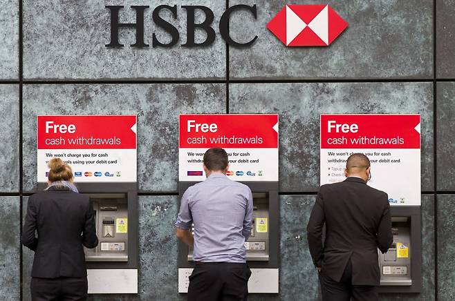 영국계 대형은행인 HSBC가 영국 내 오프라인 지점 25%를 줄이기로 결정했다. 사진은 영국 런던 HSBC 한 지점의 ATM에서 현금을 인출하는 고객들/ ⓒAFP=뉴스1