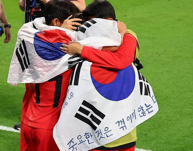 3일 오전(한국시각) 카타르 알라이얀의 에듀케이션 시티 스타디움에서 열린 2022 카타르 월드컵 조별리그 H조 3차전 대한민국과 포르투갈 경기. 포르투갈을 2-1로 이기며 16강 진출에 성공한 뒤 태극기로 어깨를 감싼 선수들이 기뻐하고 있다. 태극기 하단에 \"중요한 것은 꺾이지 않는 마음\"이라는 손글씨가 쓰여 있다. 알라이얀/김혜윤 기자 unique@hani.co.kr