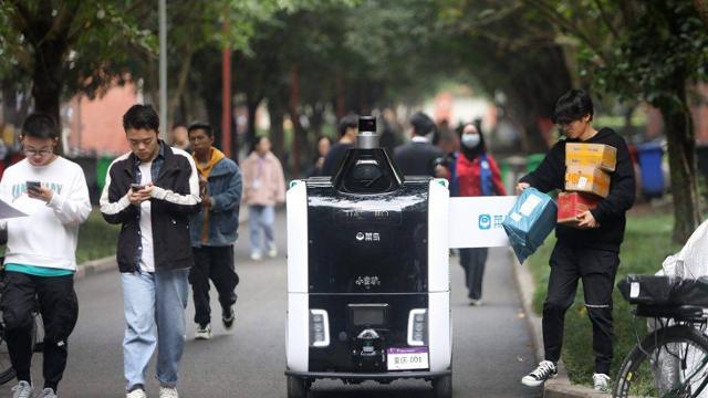 11월 11일 글로벌 쇼핑 페스티벌 기간 동안 중국의 한 대학 캠퍼스에서 학생이 알리바바에서 운영하는 무인 배달로봇 샤오만뤼에서 택배를 꺼내고 있는 모습. 알리바바 제공