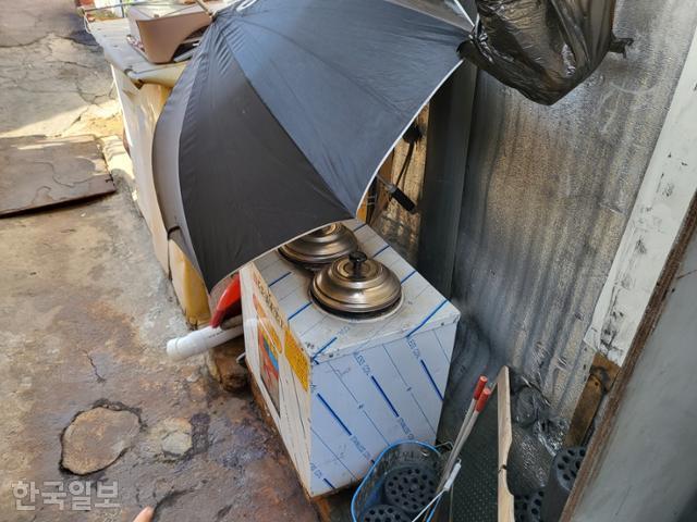 지난달 28일 서울 강남구 구룡마을 주민 조경일씨가 집 앞 연탄보일러를 우산으로 덮어놨다. 처마에 새는 비를 막으려 해놓은 임시 조치다. 강지수 기자