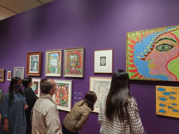 관람객들이 전시 초입 벽에 붙은 쿠사마의 자화상들을 감상하고 있다.