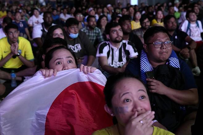 5일(현지 시각) 카타르 도하에 설치된 팬 존에서 축구 팬들이 일본 대 크로아티아 전을 보면서 놀라고 있다.  AP 뉴시스