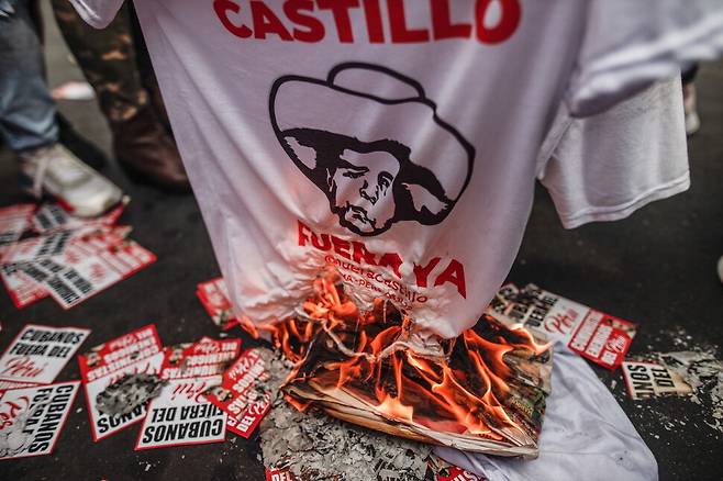 7일(현지시각) 페루 리마에서 탄핵된 페드로 카스티요 전 대통령에 반대하는 시위대가 그의 얼굴 그림과 이름이 그려진 옷을 불태우고 있다. 리마/EPA 연합뉴스