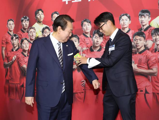 8일 청와대 영빈관에서 열린 축구 국가대표팀 환영 만찬에서 주장 손흥민 선수가 2022 카타르 월드컵 기간 착용했던 주장 완장을 윤석열 대통령에게 채워주는 모습. 연합뉴스