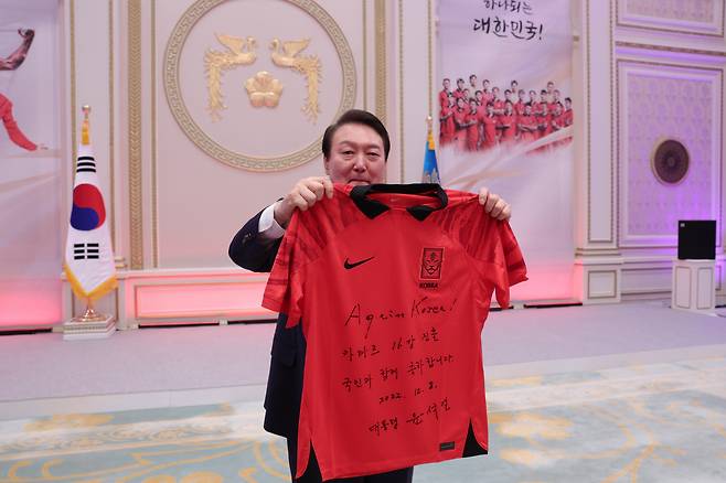 '16강 진출 국민과 함께 축하합니다' 윤석열 대통령이 8일 청와대 영빈관에서 열린 축구 국가대표팀 환영 만찬에서  '카타르 16강 진출 국민과 함께 축하합니다'라고 적은 유니폼을 손흥민 선수에게 전달하기 앞서 들어보이고 있다. 2022.12.8 [대통령실 제공, 재판매 및 DB 금지]<저작권자(c) 연합뉴스, 무단 전재-재배포 금지>