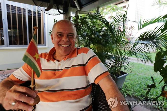 수리남 깃발을 들고, 오렌지색 상의를 입은 수리남 사람.  [AFP=연합뉴스]