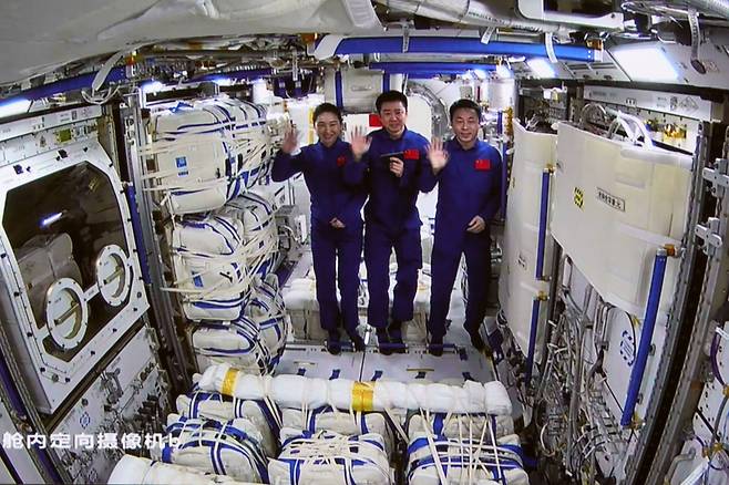 2022년 11월 중국 베이징 항공우주 관제센터에서 포착된 이 화면 이미지는 선저우-14 우주비행사 3명이 멍톈 실험실 모듈 안에서 손을 흔들고 있다.  선저우-14호와 선저우-15호 승무원들은 이후 중국 우주 역사상 최초로 궤도 내 승무원 로테이션을 실시했다. 연합/신화