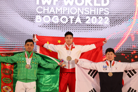 Bronze medalist Kim Woo-jae, right, gold medalist Li Dayin of China, center, and silver medalist Rejepbay Rejepov of Turkmenistan pose during the awards ceremony after the men's 81 kilogram event at the 2022 World Weightlifting Championships in Bogota, Colombia, on Sunday. [XINHUA/YONHAP]