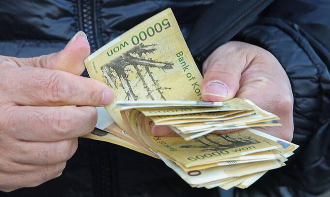 한 은행 ATM에서 시민이 현금 5만원권을 세고 있다. 뉴시스