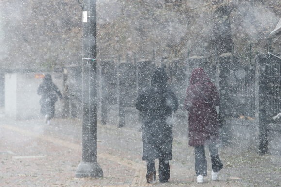 서울을 비롯한 수도권에 눈이 내리고 있는 13일 오후 서울 송파구 잠실역 인근에서 시민들이 모자를 쓰고 이동하고 있다 [사진=뉴시스 ]