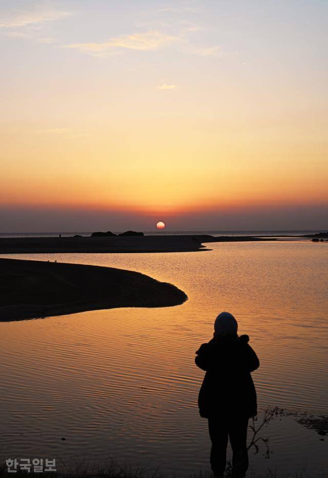평해사구습지의 일출 풍경. 가느다란 모래 언덕을 사이에 두고 먼바다에서 해가 뜨면 붉은 기운이 남대천 수면에 번진다.