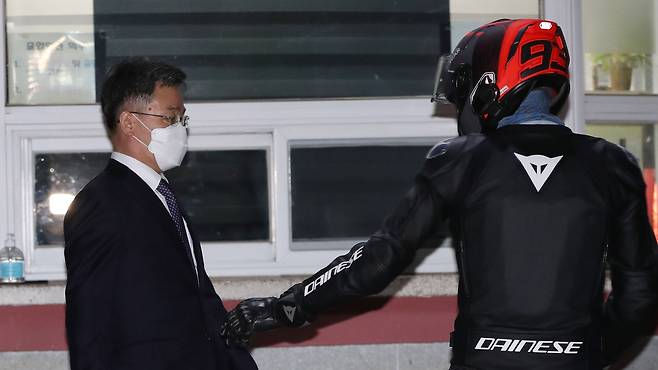 경기 성남시 대장동 개발사업 특혜 의혹의 핵심 인물이자 화천대유의 대주주 김만배 씨가 15일 새벽 경기도 의왕시 포일동 서울구치소에서 구속영장이 기각된 후 밖으로 나와 바이크 헬멧을 쓴 누군가의 도움을 받고 있다.   바이크를 타고 온 이 남자는 김씨를 보호해 차에 태운 뒤 취재진이 자신에게 몰려들자 빠르게 바이크를 몰고 떠났다. 2021.10.15/뉴스1