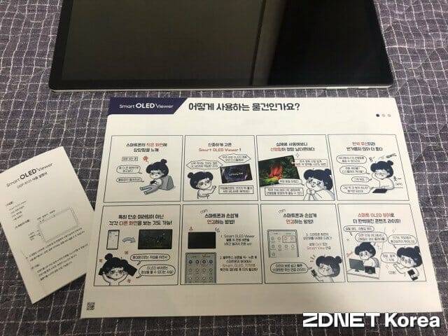 스마트 OLED 뷰어를 바닥에 두고 옆에서 보니 백라이트가 없어 얼마나 얇은지 확인할 수 있다. 설명서도 여럿 들어 누구나 쉽게 쓸 수 있다.(사진=유혜진 기자)