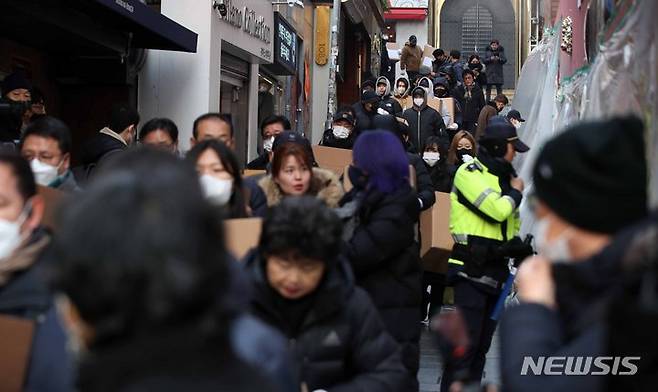 [서울=뉴시스] 김선웅 기자 = 이태원 참사 유가족협의회, 이태원 상인회, 자원봉사자 등이 21일 서울 용산구 이태원역 인근에 마련된 추모공간에서 참사 추모물품과 추모메시지 등을 정리하기 위해 상자를 운반하고 있다.  2022.12.21. mangusta@newsis.com