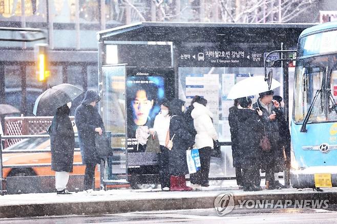 눈 속 버스 기다리는 시민들 (서울=연합뉴스) 박동주 기자 = 서울 전역에 대설주의보가 발효된 21일 오전 서울 시내의 모습. 2022.12.21 pdj6635@yna.co.kr