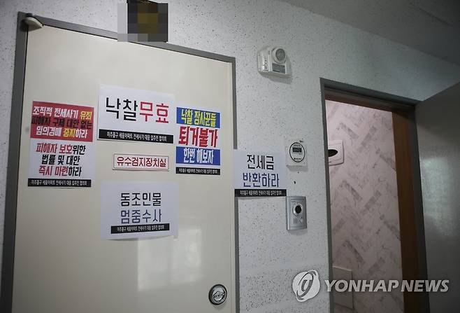 '전세사기 아파트 낙찰 무효' (인천=연합뉴스) 최은지 기자 = 지난 20일 찾은 인천시 미추홀구의 한 전세 사기 피해 아파트 현관에 낙찰 무효와 퇴거 불가를 주장하는 임차인들의 문구가 붙어 있다. 2022.12.21 chamse@yna.co.kr