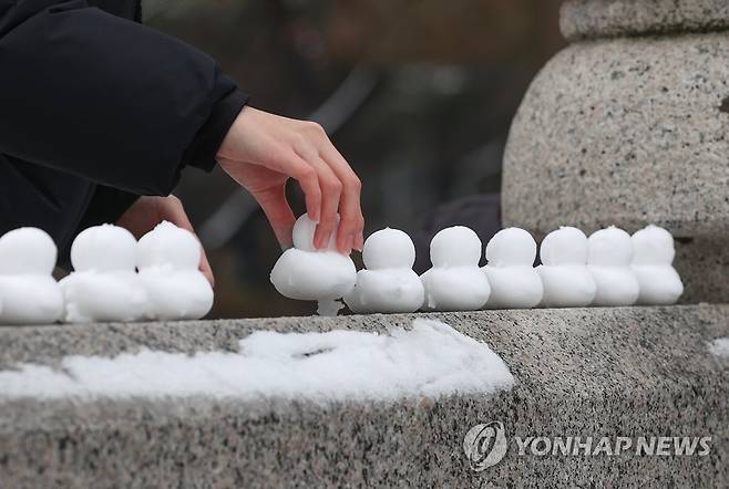 청계천 눈오리 (서울=연합뉴스) 신현우 기자 = 전국 곳곳에서 눈이 내린 21일 오후 서울 중구 청계천 광통교에서 한 시민이 눈오리를 만들고 있다. 2022.12.21 nowwego@yna.co.kr