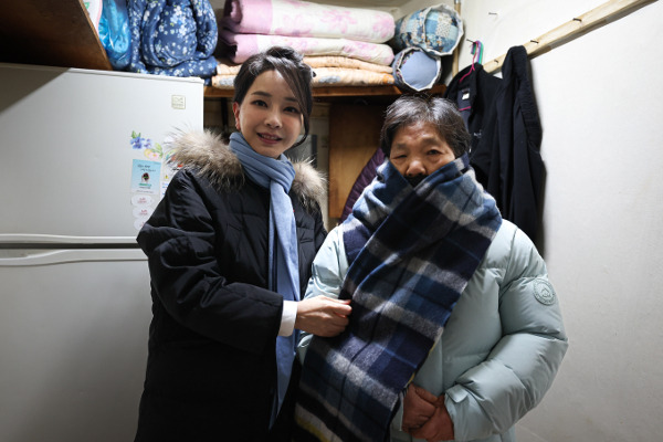 김건희 여사가 22일 서울 남대문 쪽방촌을 찾아 한 주민에게 머플러와 점퍼를 선물하고 있다. 김 여사는 이날 구세군이 주관하고 사단법인 굿피플인터내셔널이 후원하는 ‘이웃과 함께하는 2022 찾아가는 성탄절, 희망박스 나눔’ 행사에 참여했다. 대통령실 제공