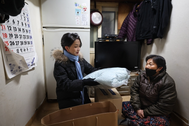 김건희 여사가 22일 서울 남대문 쪽방촌에서 열린 '이웃과 함께하는 2022 찾아가는 성탄절, 희망박스 나눔행사'에서 쪽방촌 어르신을 찾아가 식료품 등이 담긴 '희망박스'와 함께 겨울점퍼와 머플러를  전달하고 있다. 대통령실 제공