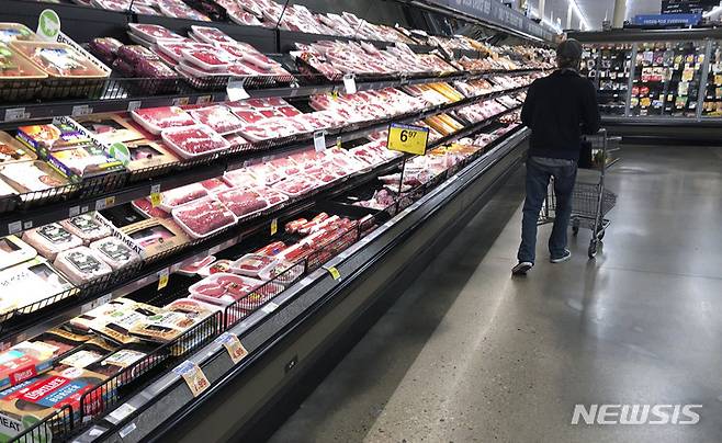 FILE - In this May 10, 2020 file photo, a shopper pushes his cart past a display of packaged meat in a grocery store in southeast Denver. Prices at the wholesale level fell from June to July, the first month-to-month drop in more than two years and a sign that some of the U.S. economy's inflationary pressures cooled last month. Thursday’s report from the Labor Department showed that the producer price index