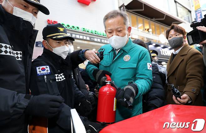 이상민 행정안전부 장관이 23일 오후 서울 중구 명동에서 연말 명동 인파대비 안전관리 실태점검 중 소방관계자에게 보이는 소화기 설명을 듣고 있다. 2022.12.23/뉴스1 ⓒ News1 박지혜 기자