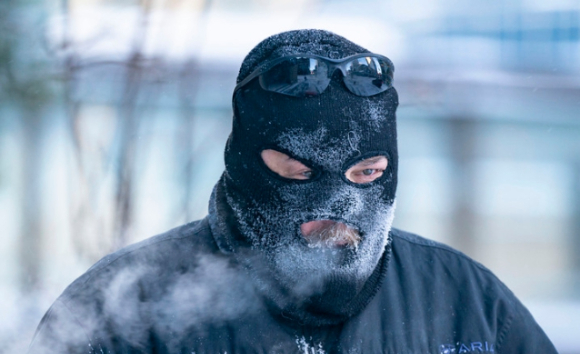 22일(현지시간) 미 미네소타주 미니애폴리스에서 추위를 막기 위해 얼굴 모자를 쓴 사람이 전동 송풍기로 보도의 눈을 치우고 있다. [사진=뉴시스]