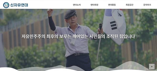 신자유연대 홈페이지 첫 화면. 김상진 대표가 태극기를 들고 손을 들고 있다. 첫 화면에 올라온 ‘자유민주주의 최후의 보루는 깨어있는 시민들의 조직된 힘입니다’라는 모토는 노무현 전 대통령의 발언 앞에 ‘자유’를 덧붙인 것이다.  /신자유연대 홈페이지 캡처