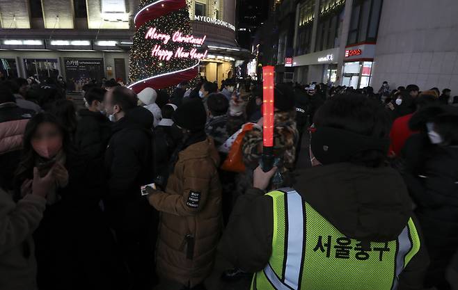 [서울=뉴시스] 최진석 기자 = 크리스마스 이브인 24일 서울 중구 명동거리에서 서울 중구 관계자가 질서 유지를 위해 경광봉을 흔들고 있다. 2022.12.24. myjs@newsis.com