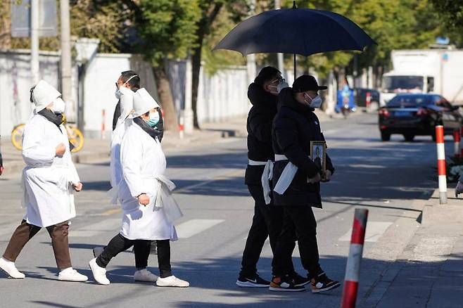 23일 중국 상하이의 장례식장에서 마스크를 쓴 유가족들이 고인의 영정을 옮기고 있다.로이터연합뉴스