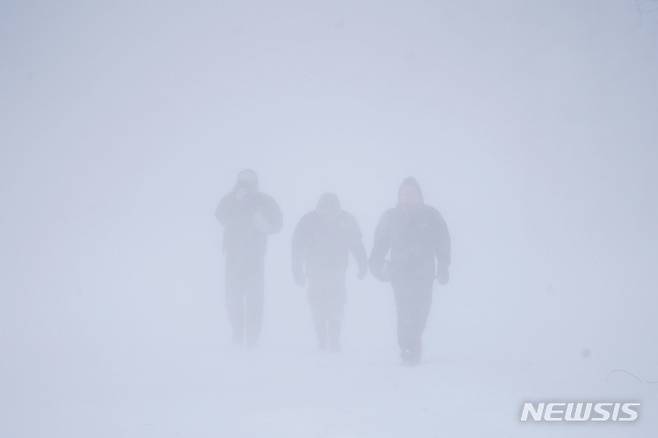 [뉴욕=AP/뉴시스]24일(현지시간) 미국 뉴욕 버팔로에서 3명의 시민이 눈보라 속을 걷고 있다. 폭설과 강풍으로 가시거리가 제로에 가까운 '화이트아웃' 현상이 벌어지고 있다. 버팔로에는 이날 70㎝ 이상의 눈이 쌓였다.