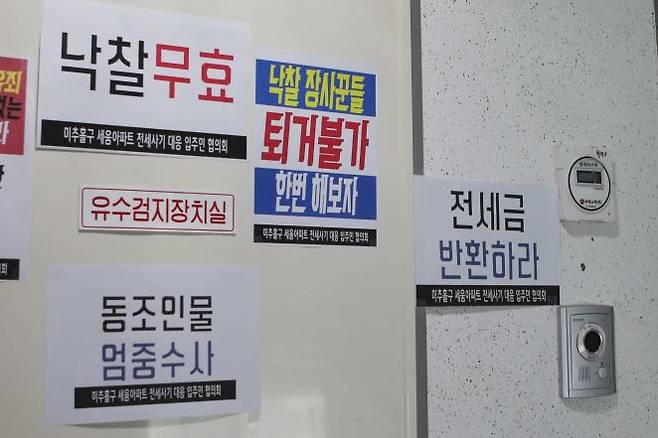 지난 20일 찾은 인천시 미추홀구의 한 전세 사기 피해 아파트 현관에 낙찰 무효와 퇴거 불가를 주장하는 임차인들의 문구가 붙어 있다. [이미지출처=연합뉴스]