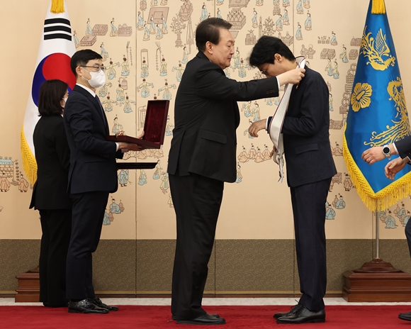 윤석열 대통령이 27일 서울 용산 대통령실 청사에서 ‘오징어게임’으로 미국 에미상 감독상을 받은 황동혁 감독에게 금관문화훈장을 수여하며 정장을 어깨에 걸어주고 있다. 2022.12.27 연합뉴스