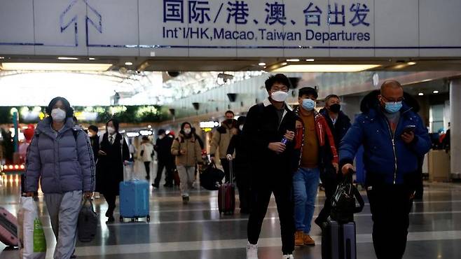 Travellers walk with their luggage at Beijing Capital International Airport