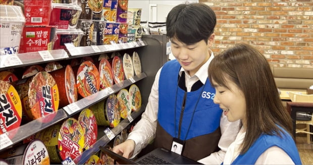 GS리테일 매니저가 GS25 매대 앞에서 가맹점주와 이야기하고 있다.    GS리테일 제공