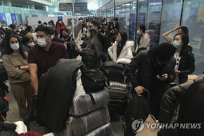 광저우 공항에서 몇 시간째 자가격리 시설로 떠나는 버스를 기다리는 여행객들 [AP=연합뉴스]