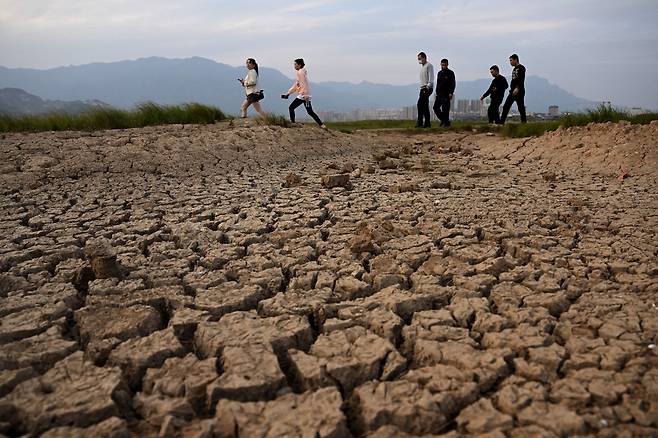 This photo taken on November 5, 2022, shows tourists walking at the dried-up freshwater Poyang Lake in J중국 장시성 호수가 극심한 가뭄으로 마르자 관광객이 그 위를 걸어가고 있다. [AFP]