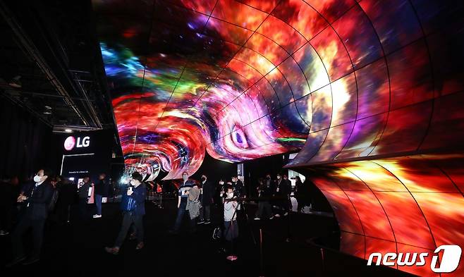 세계 최대 전자·가전·정보기술(IT) 전시회인 CES 2023 개막을 하루 앞둔 4일(현지시간) 미국 네바다주 라스베이거스 컨벤션센터에서 열린 LG전자 부스 사전 투어에서 취재진들이 전시관 입구에 올레드 플렉서블 사이니지 260장을 이어 붙인 초대형 조형물 ‘올레드 지평선(OLED Horizon)’ 앞을 지나고 있다. 2023.1.5/뉴스1 ⓒ News1 임세영 기자