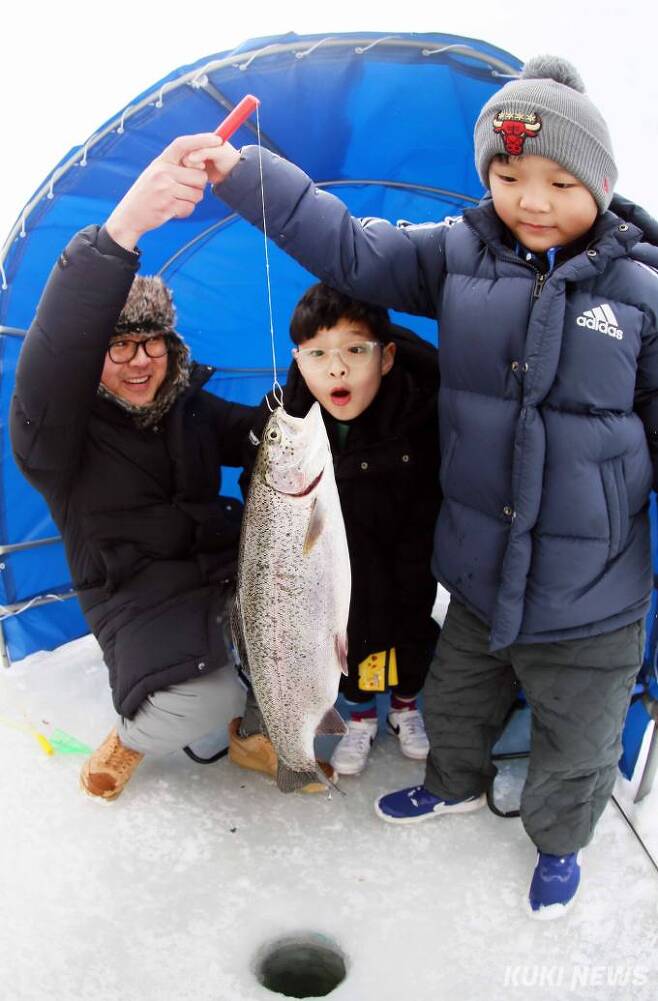 "아빠 내가 잡았어요" 생전 처음 송어를 낚은 어린 강태공이 얼음구멍에서 올라온 대형물고기를 들어보이고 있다.