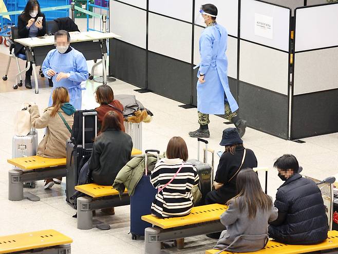 중국발 한국행 항공기에 탑승하는 모든 내·외국인의 코로나19 음성확인서 제출 의무화 첫날인 5일 오전 인천국제공항 제1여객터미널 입국장에서 방역 관계자가 중국발 입국객들을 안내하고 있다. [연합]