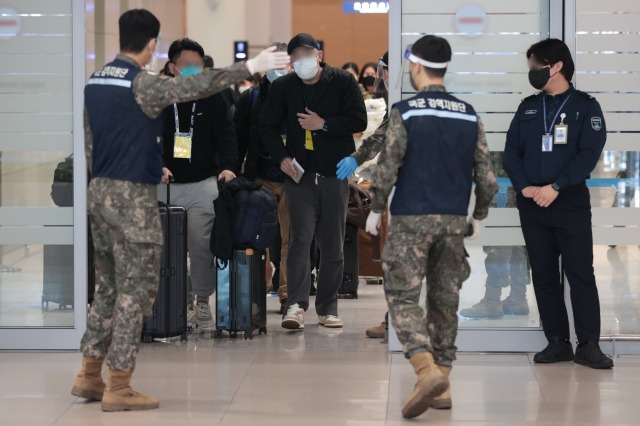 지난 9일 오전 인천국제공항 제2여객터미널에서 방역 관계자들이 중국발 입국자들을 코로나19 검사센터로 인솔하고 있다. 연합뉴스