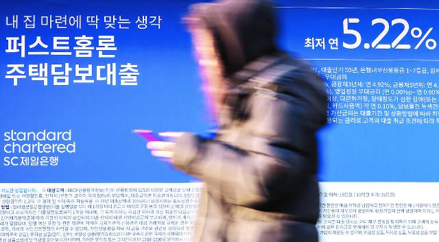 은행의 과도한 ‘이자 장사’를 비판하는 목소리가 커지자 NH농협은행 등은 12일 주택담보대출 금리 인하 계획을 밝혔다. 사진은 이날 서울 한 시중은행에 대출 상품 광고판이 붙어 있는 모습. 연합뉴스